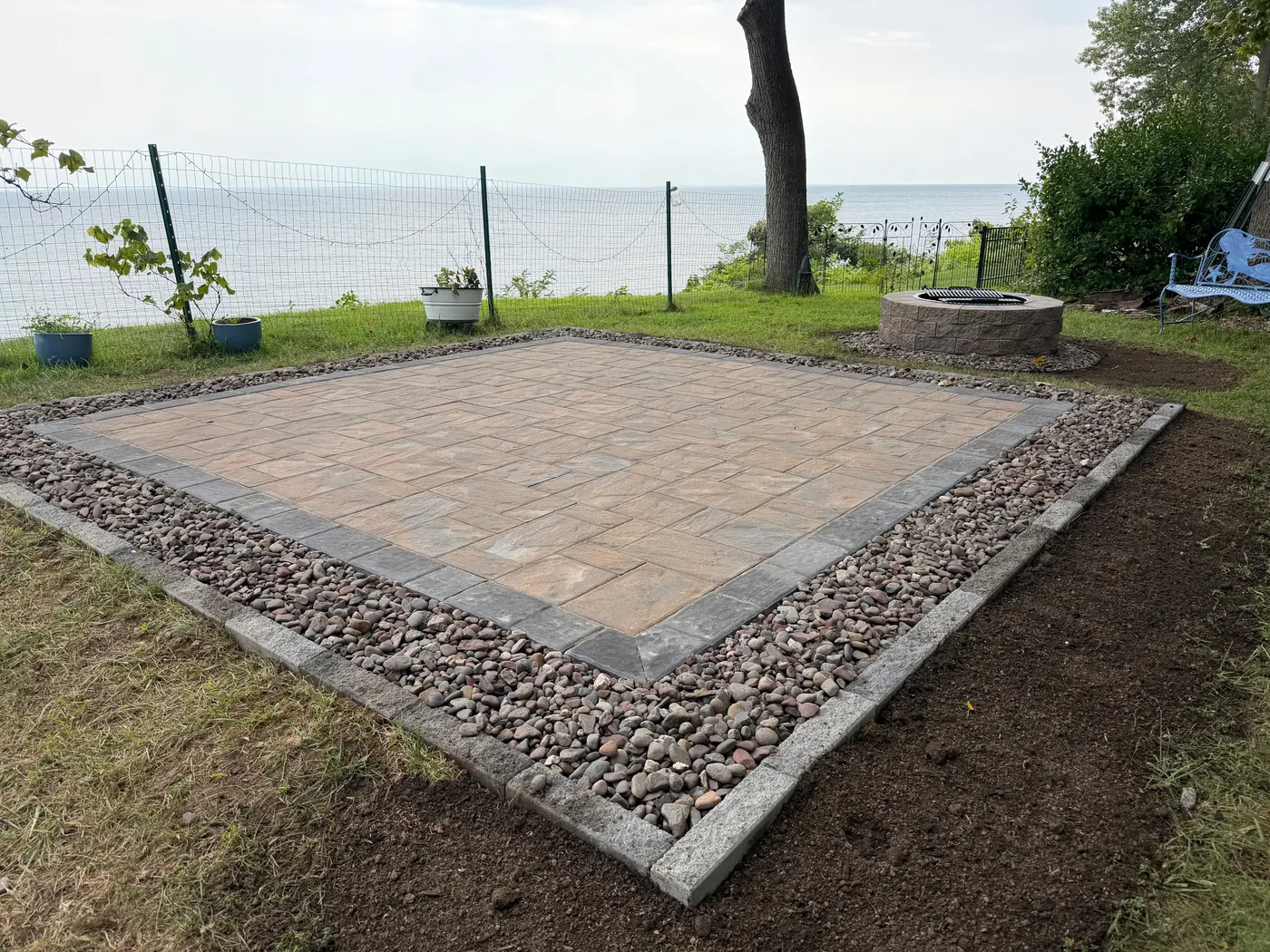 Paver patio edged with gravel on a waterfront lawn